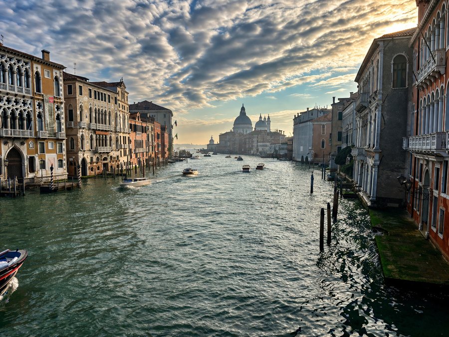 Grand Canal in Venice lined with historic buildings, with boats on the water and the domed Santa Maria della Salute in the distance.